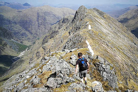 Mies vaeltaa vuorten harjanteella.