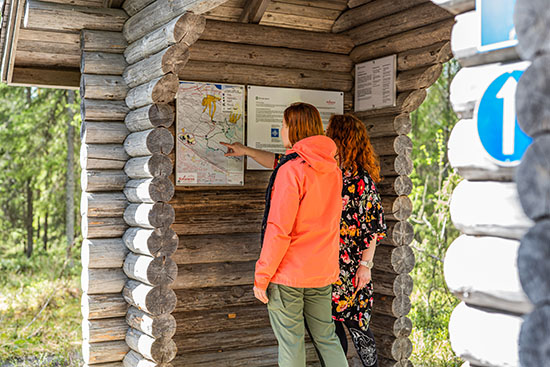 Kuvassa kaksi nuorta naista katselevat retkeilualueen karttaa.