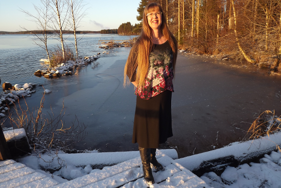 Kuvassa Anna Kekki seisoo lumisella rannalla järvimaisemassa.