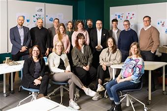 Ryhmäkuva muotoilun tutkinto-ohjelman opettajista, asiantuntijoista ja opiskelijoista sekä työelämän edustajista muotoilun luokkatilassa.