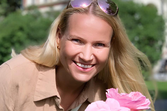 Kuvassa hymyilevä Marjaana Kangas vihreää taustaa vasten.