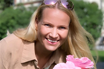 Kuvassa hymyilevä Marjaana Kangas vihreää taustaa vasten.