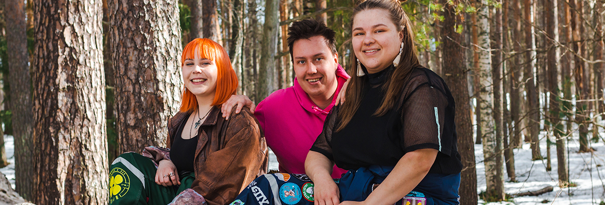 Opiskelijahaalareihin pukeutuneita yhteiskuntatiedeiden tiedekunnan opiskelijoita istumassa yliopistokampuksen takametsässä