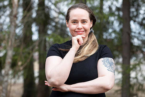 Jenna Päläs, taustalla havupuita.